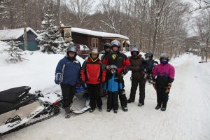 8 people getting ready to take off on snowmobiles